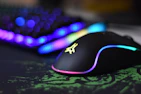 A close-up of a sleek gaming mouse glowing with customizable LED lights on a dark desk.