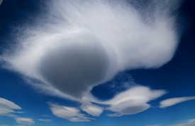 Unique cloud formations with smooth, rounded shapes float against a deep blue sky, creating a surreal and tranquil atmosphere.