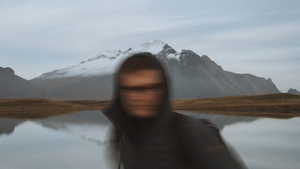 Una foto sfocata di un uomo in piedi di fronte a un lago