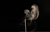 Gentle smoke rising from burning Acacia Confusa incense in a serene, natural setting.