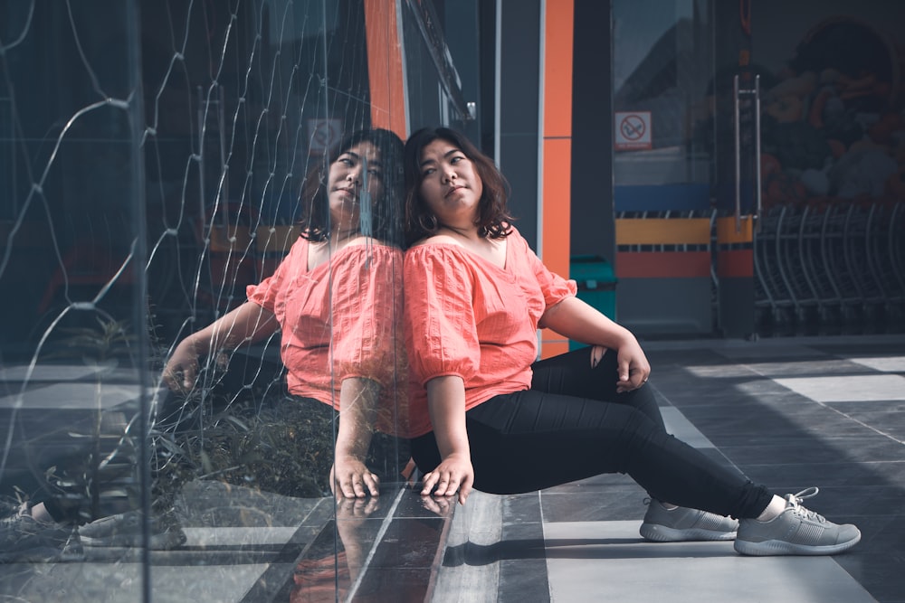 woman in pink blouse lean on glass wall