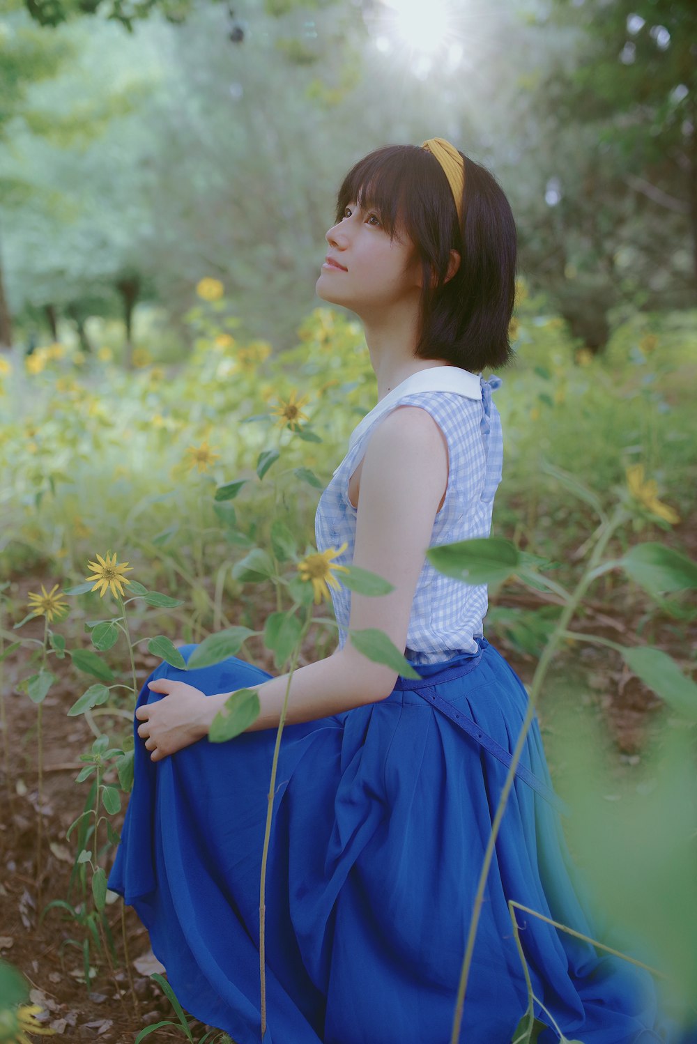 woman standing under tree surrounded by yellow flowers