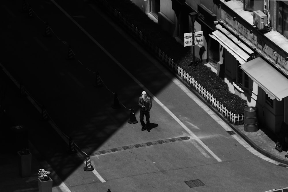 grayscale photography of person standing at road