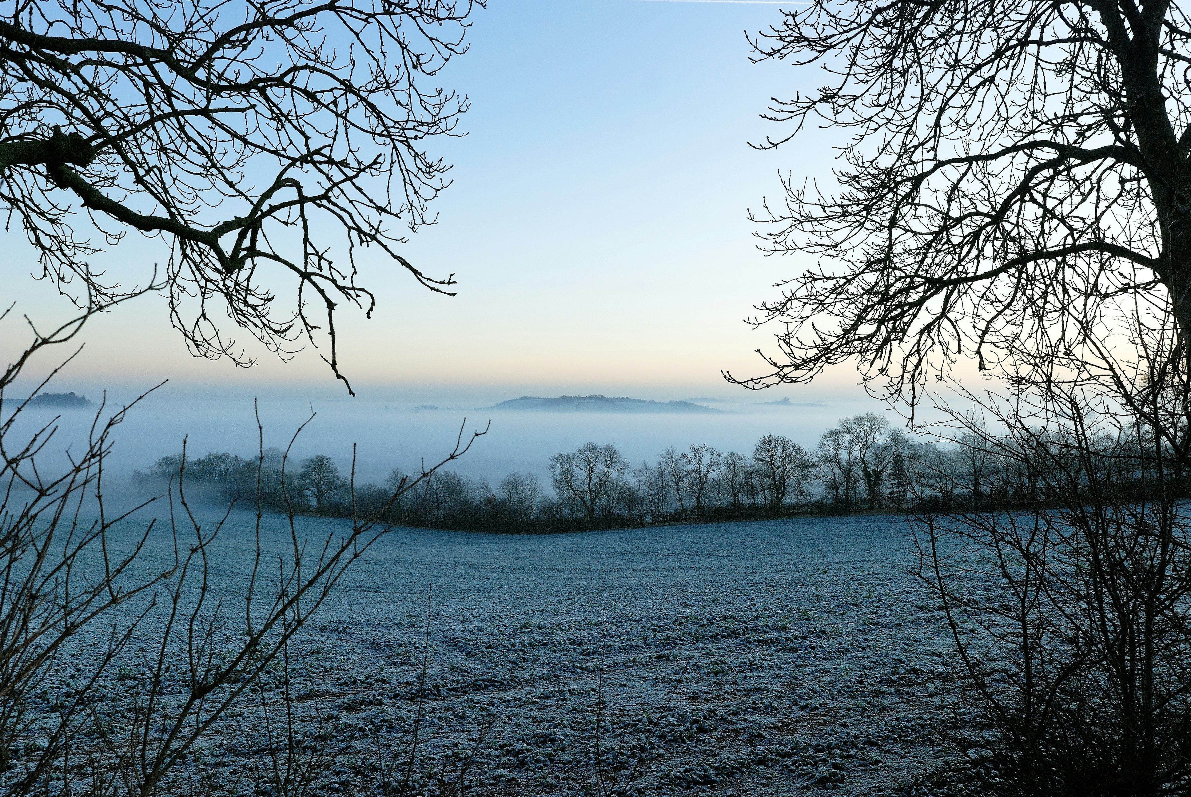 Looking out over a cold and frosty Cotswold countryside complete with mist created by and trapped by a thermal inversion layer in the valley bottom.  This gives a very flat top to the mist and can be very effective.   In eight years living in this particularly hilly and frosty part of the Cotswold’s, I only saw this a couple of times.