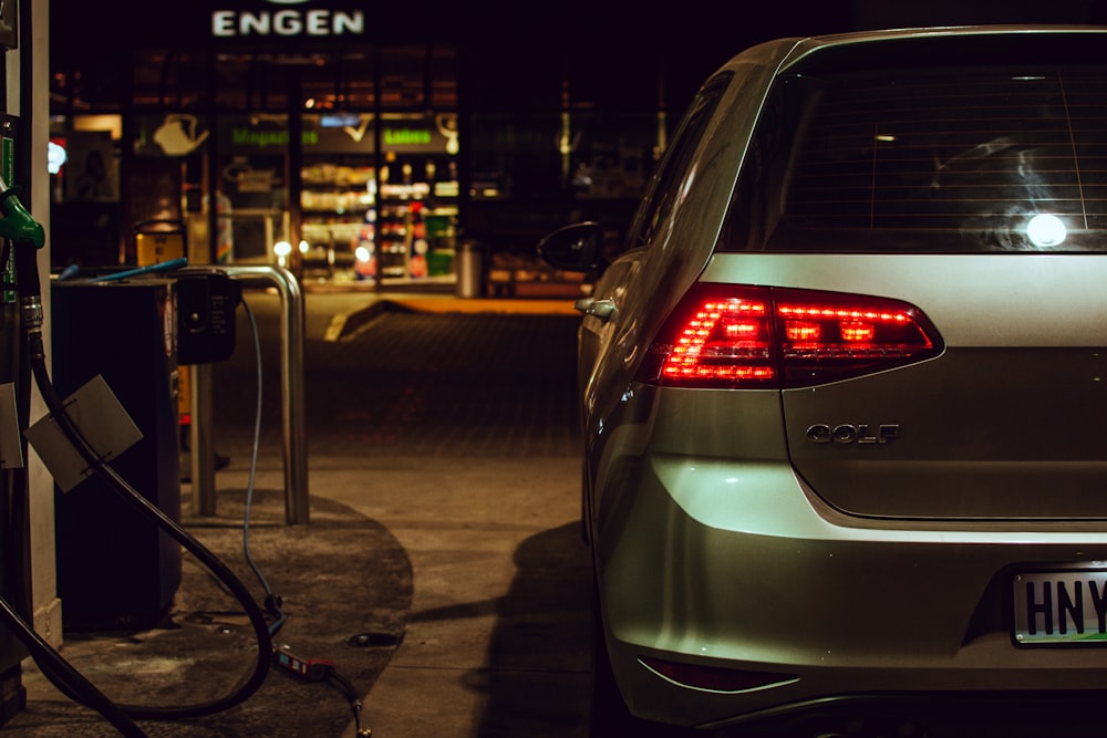 silver Volkswagen Golf station wagon parked beside gas pump during nighttime