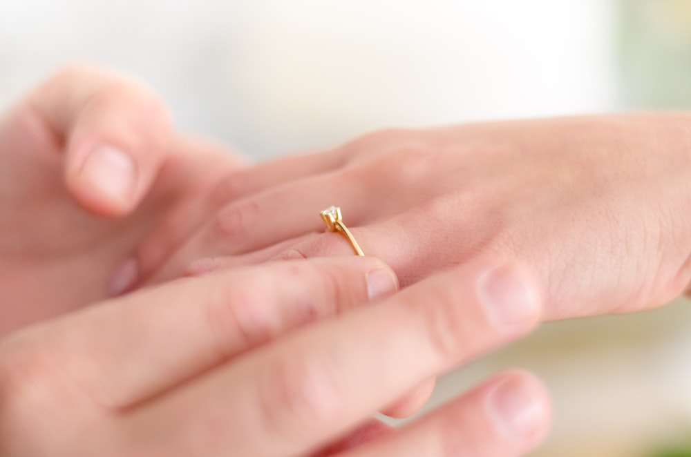 shallow focus photo of person putting gold-colored ring Choosing an Engagement Ring