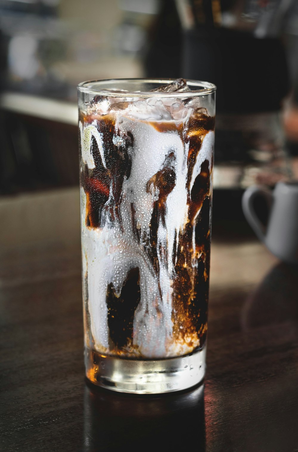 copo de vidro transparente cheio de chocolate na mesa de madeira marrom