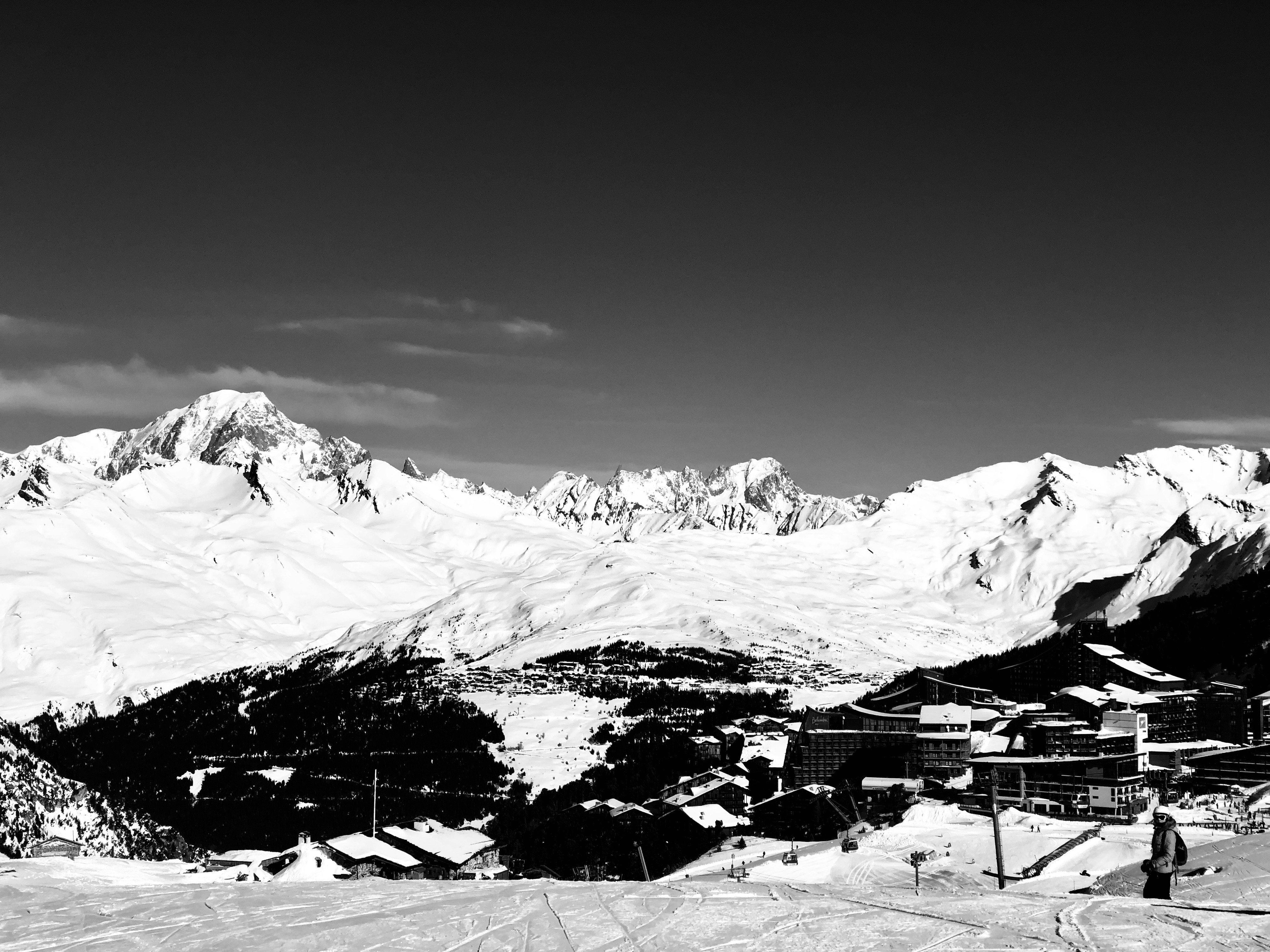 Snow-covered mountain ski resort at dusk, deep shadows in valley, dramatic alpine atmosphere, dark sky