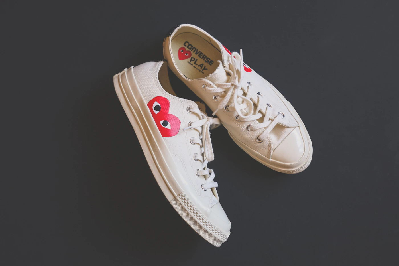 White sneakers photographed against a dark background