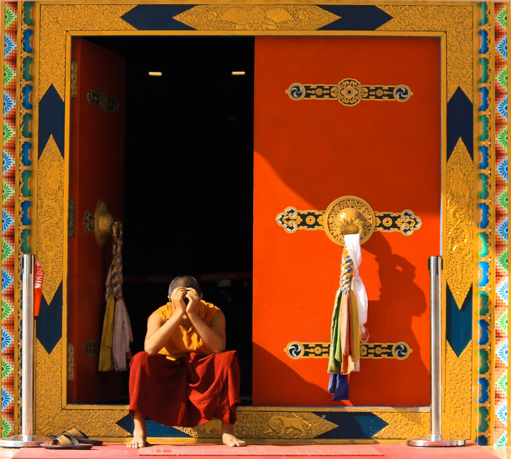 man in orange top sitting beside door