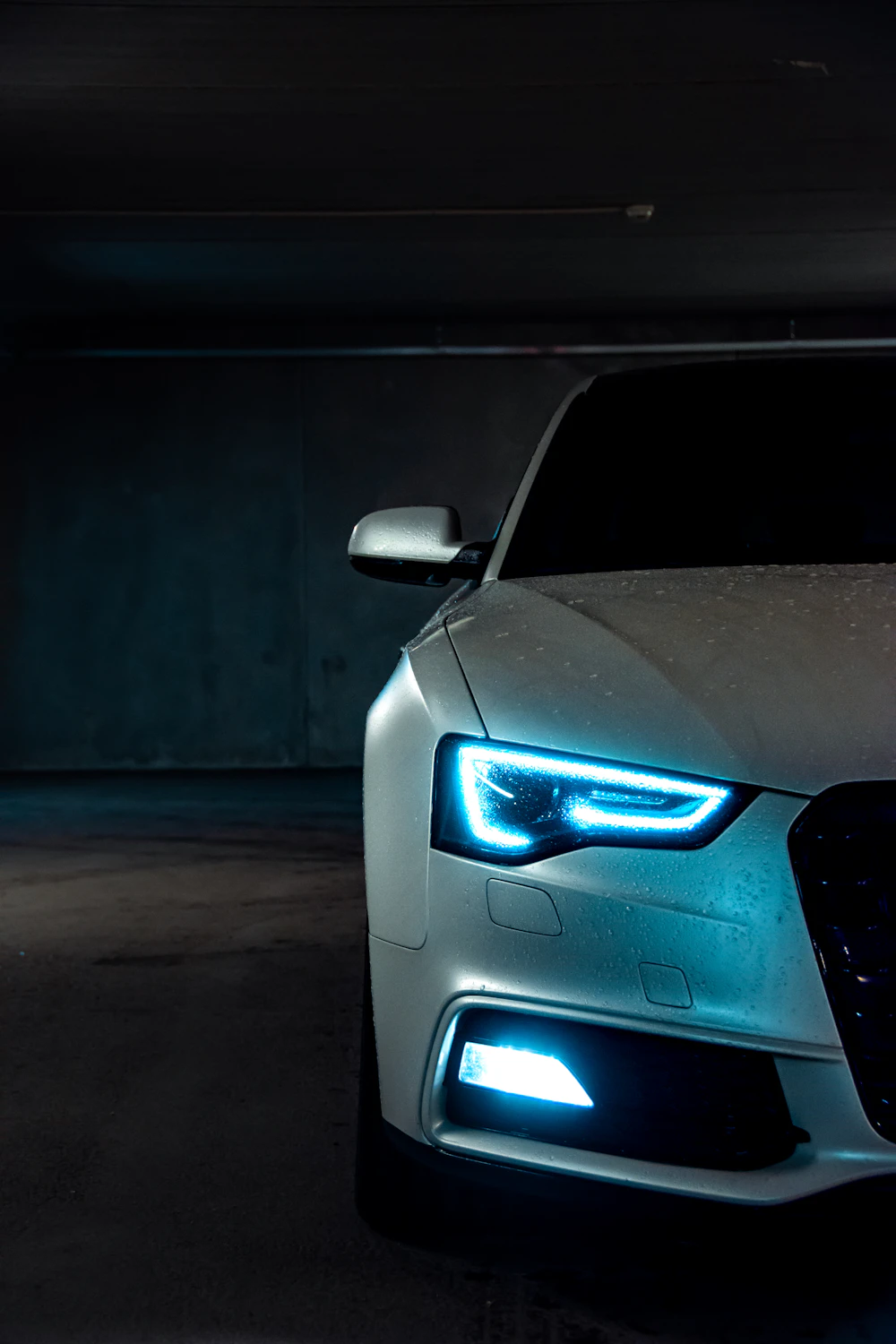 White car with glowing headlights in a dark garage