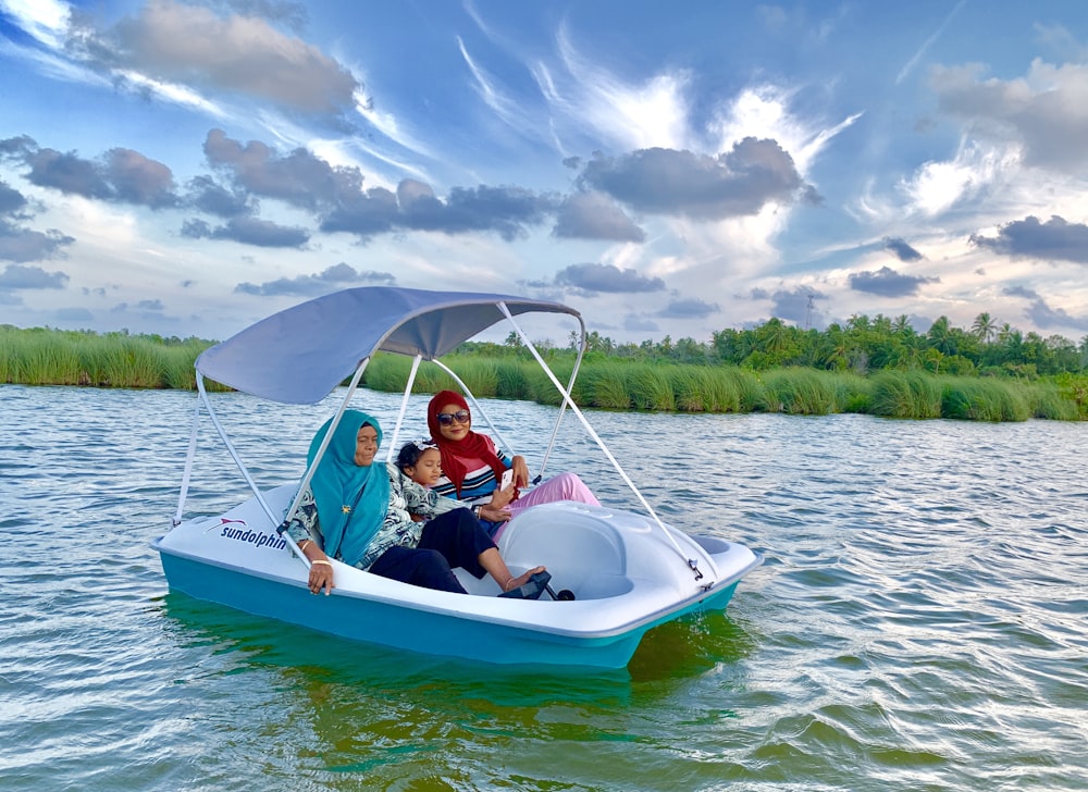 three person riding boat on body of water
