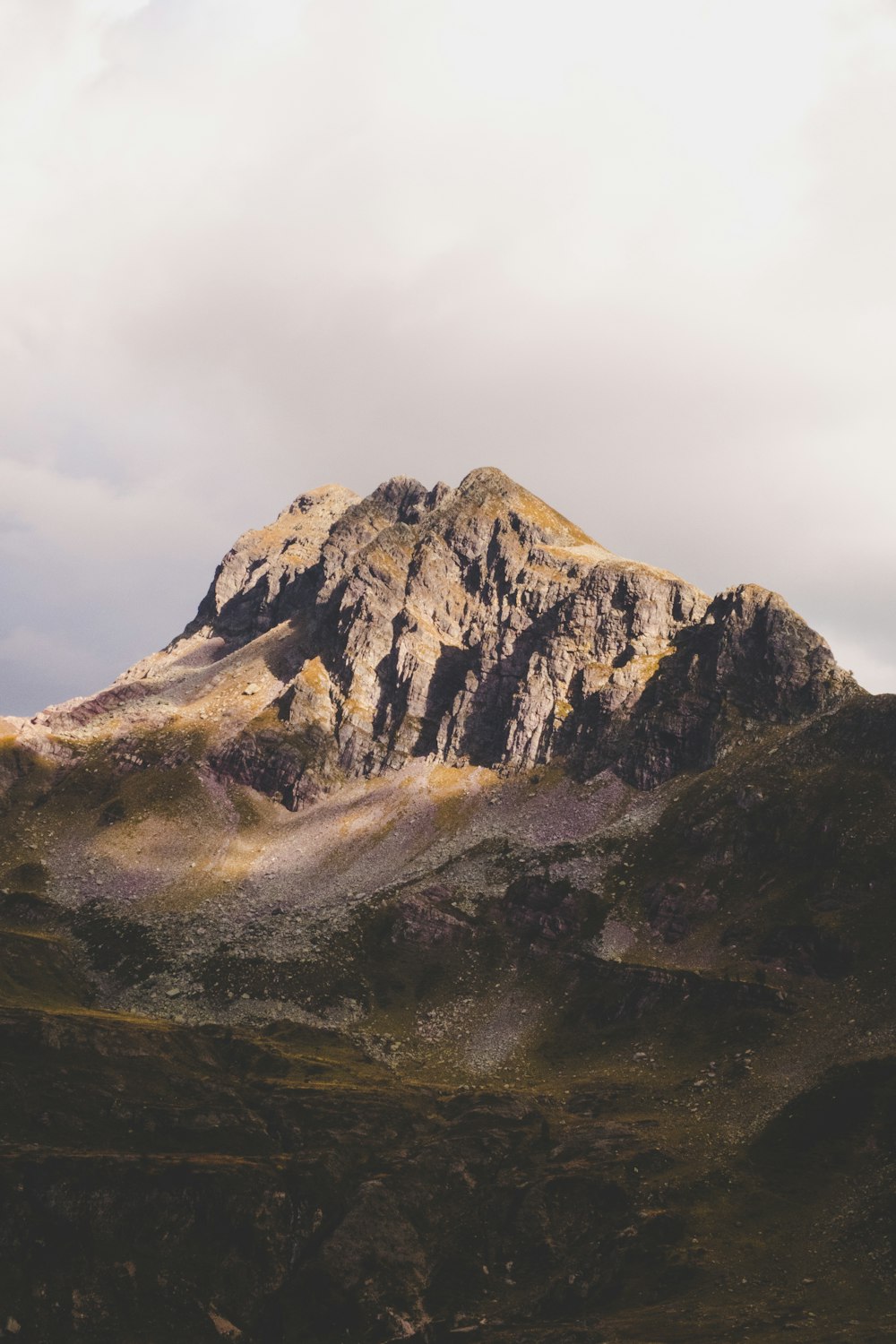 brown and green mountain under cloudy skies