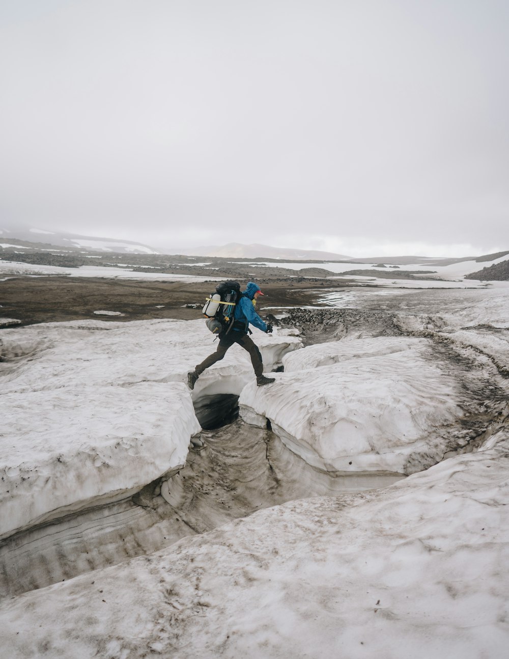 person waering teal jacket walking on icy surface