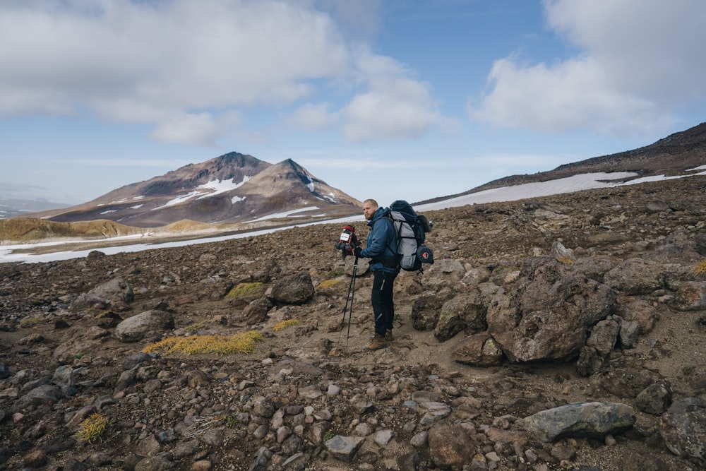 man carrying hiking bag on mountain slope