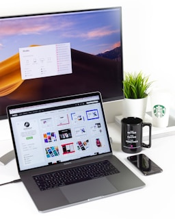laptop near mug and computer monitor