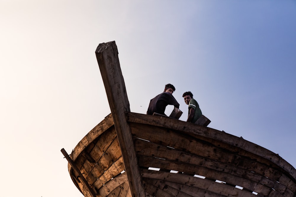 two men sitting on brown boat