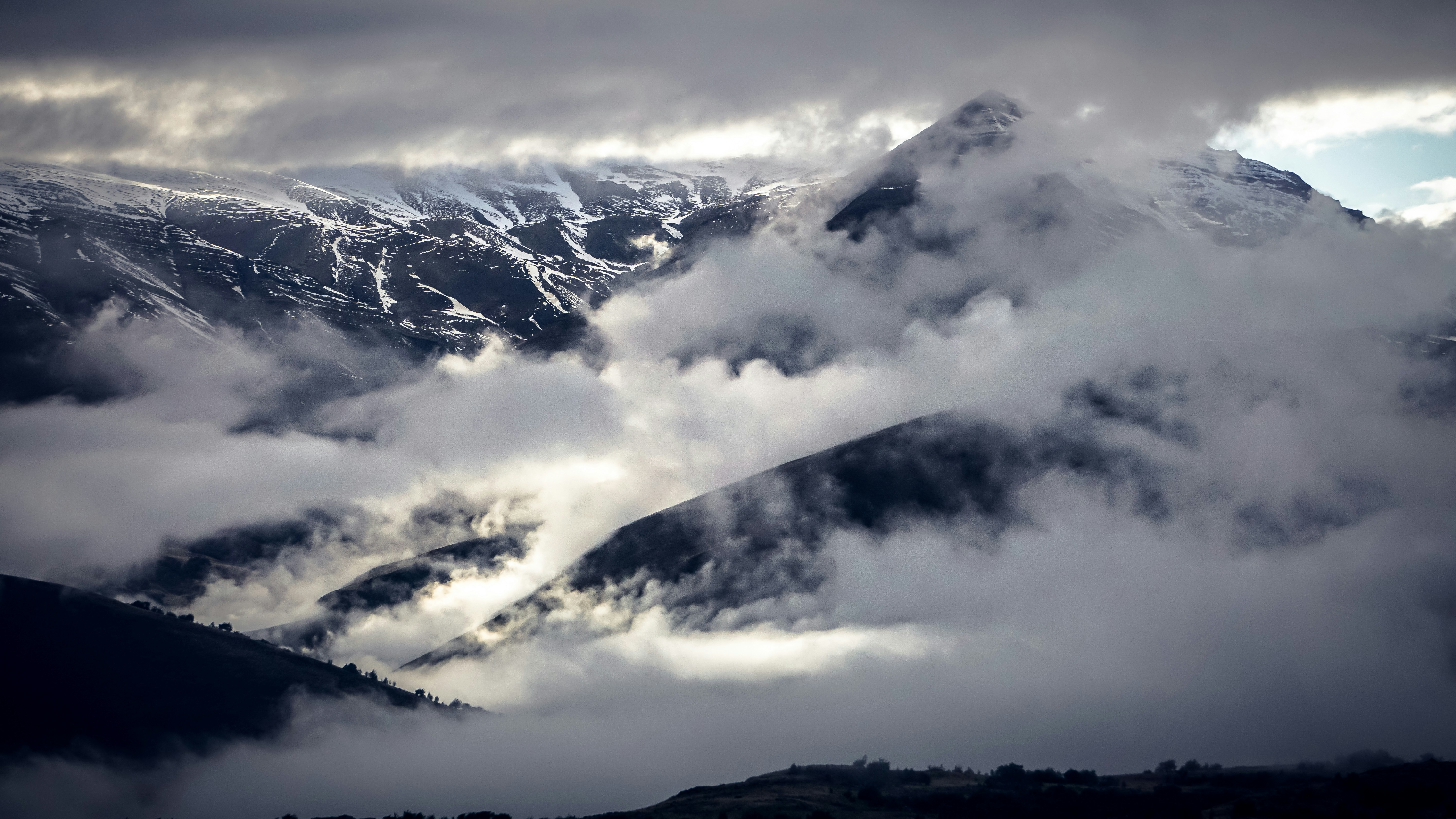 fogs covering rocky mountain under cloudy sky during daytime