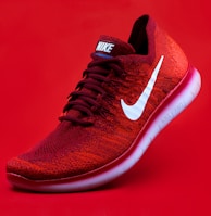 unpaired red Nike sneaker