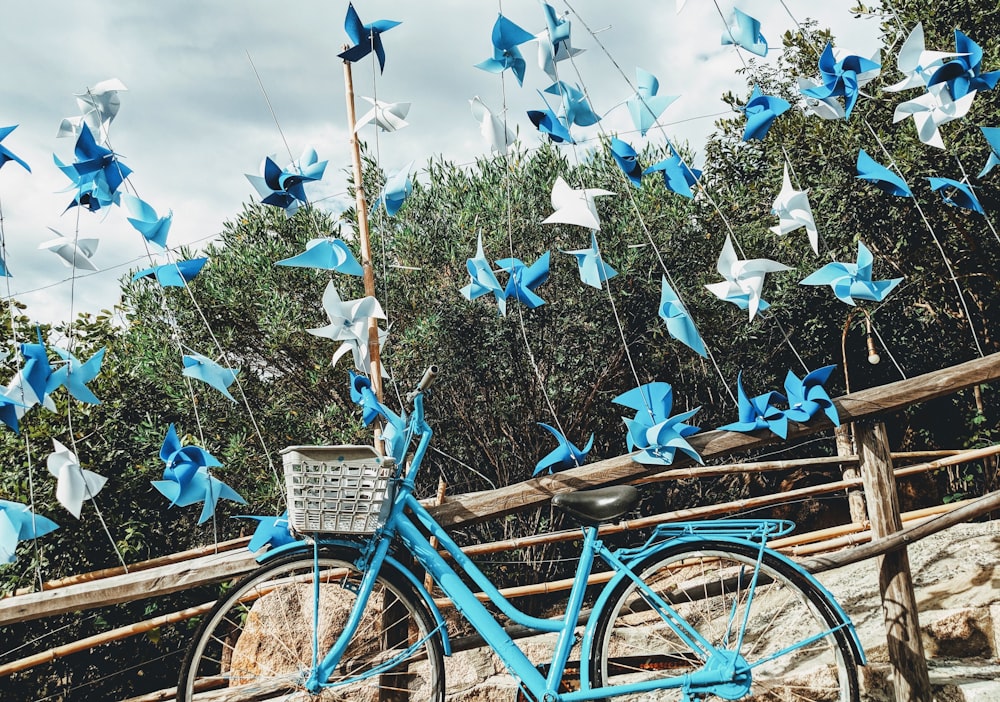 blue bicycle beside brown wooden fence during daytime