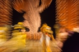 Blurred motion capture of colorful characters amidst a backdrop of vibrant lights, with a central figure outlined by fireworks patterns.