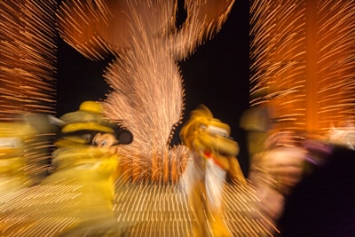 Blurred motion capture of colorful characters amidst a backdrop of vibrant lights, with a central figure outlined by fireworks patterns.