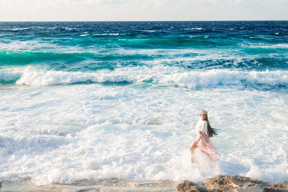 woman walking on seashore with ocean waves