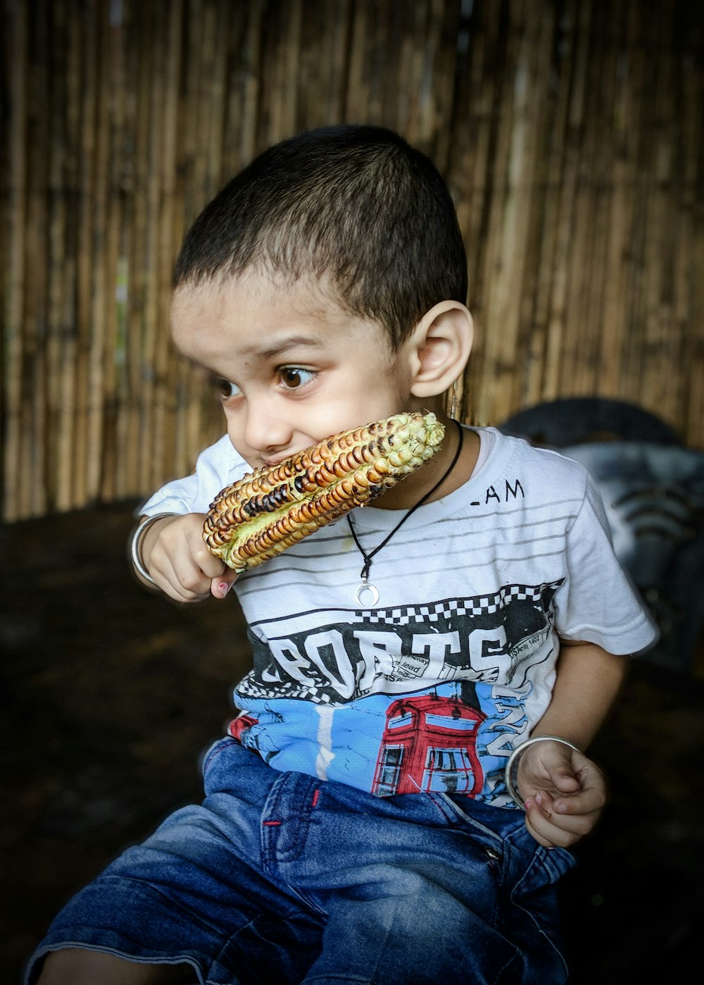 um menino comendo um milho na espiga
