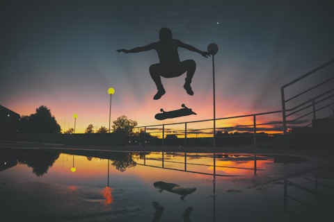 silhouette of skateboard player doing exhibition on park