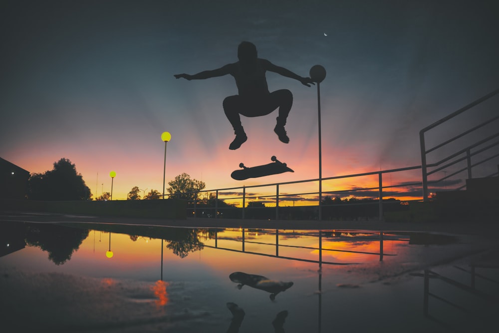 silhouette of skateboard player doing exhibition on park