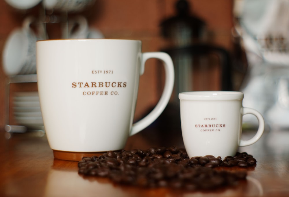 photographie sélective de deux tasses en céramique Starbucks blanches