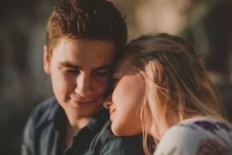 A tender moment between two people is captured as they lean comfortably against each other. The warm lighting creates a serene and intimate atmosphere.