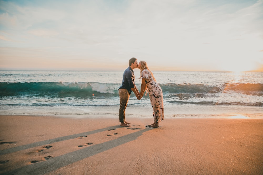 man and woman kissing on seashore