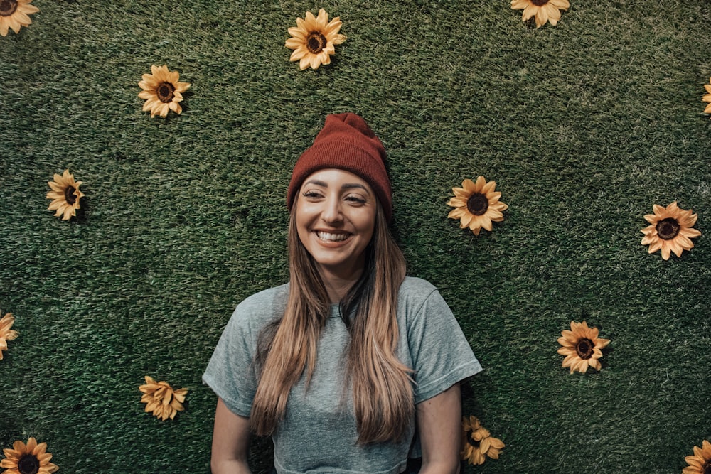 Mulher sorridente apoiada na parede floral