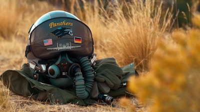 grey aviator helmet and gears on grass ground