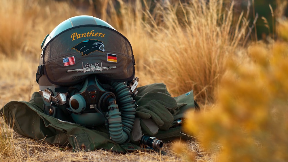 grey aviator helmet and gears on grass ground