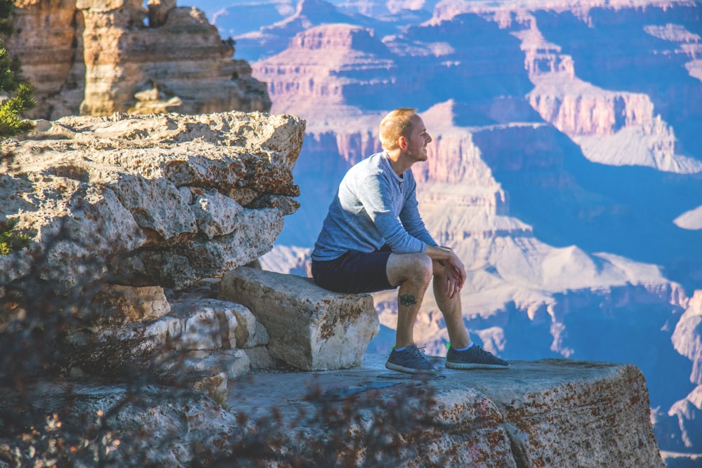 man sitting on cliff mountain