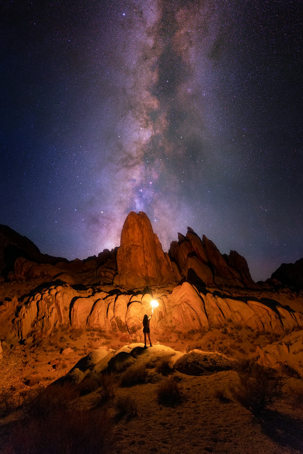silhouette of person standing on rock formation under starry night