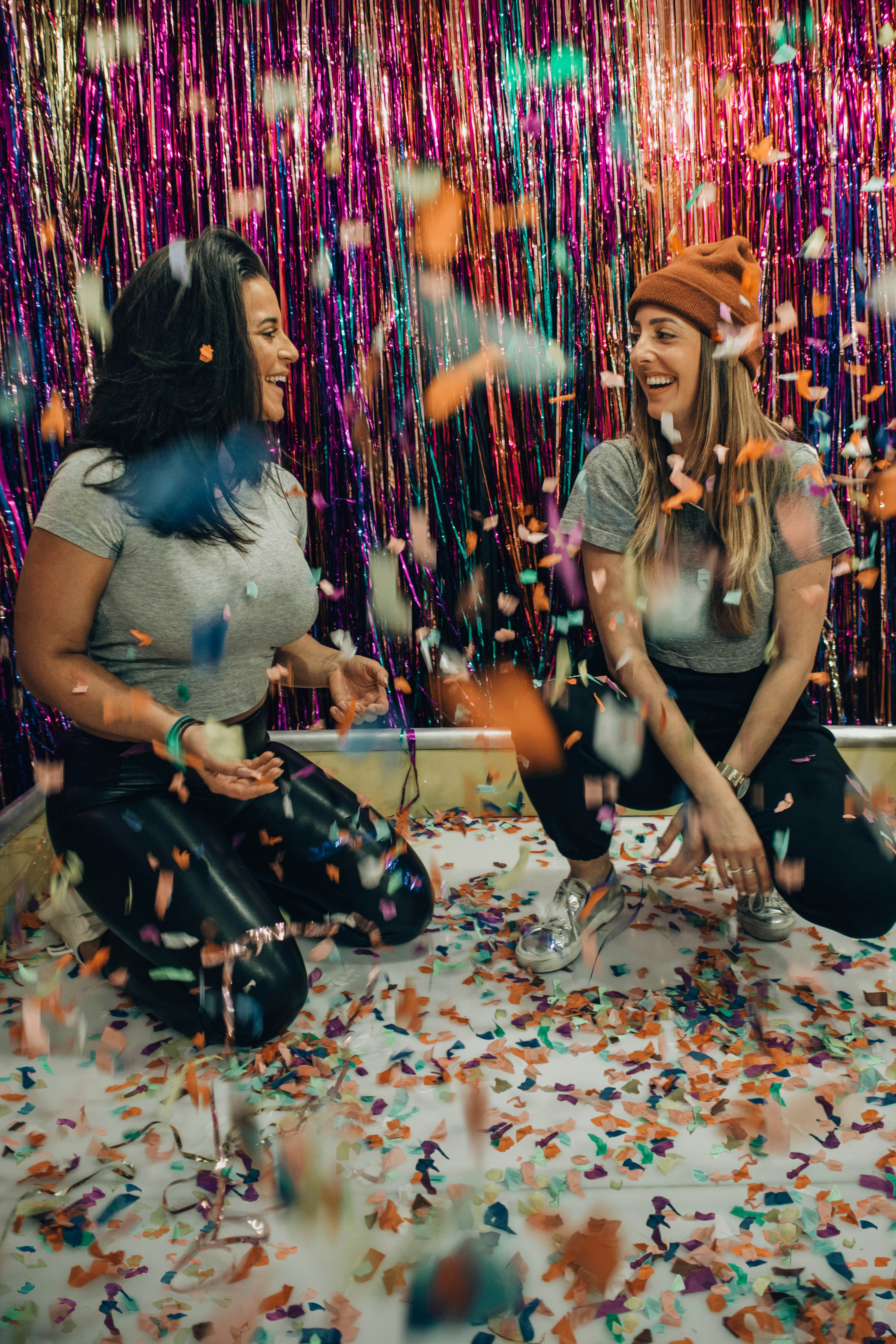 two women kneeling under falling confetti