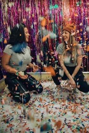 two women kneeling under falling confetti