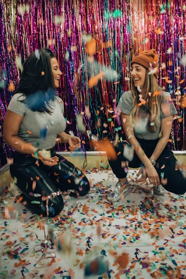 two women kneeling under falling confetti