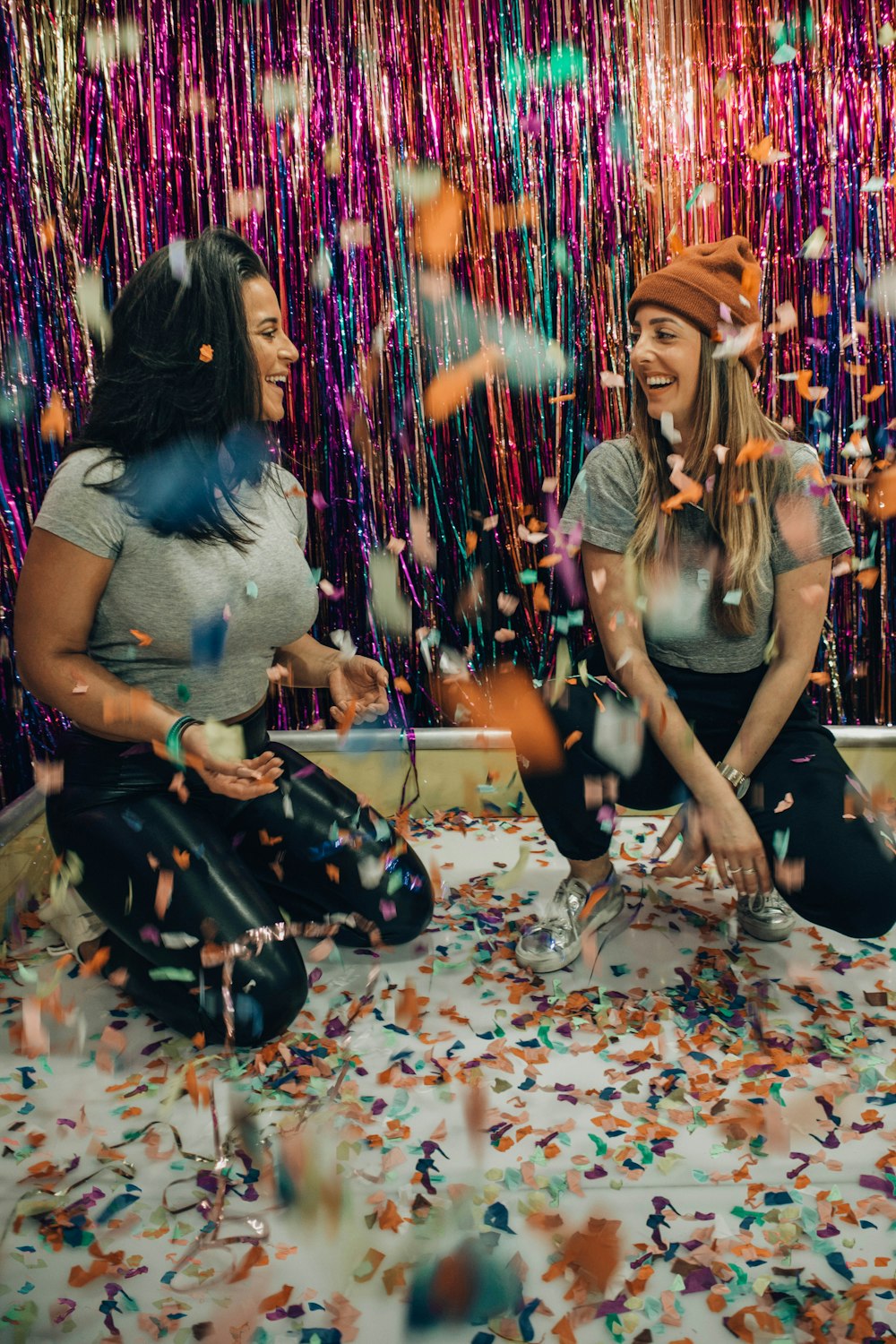 two women kneeling under falling confetti