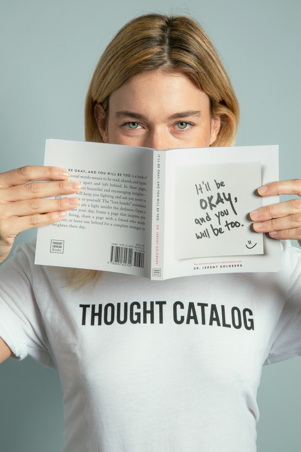 woman hiding his mouth using book