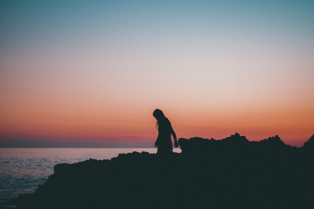 silhouette of woman near body of water