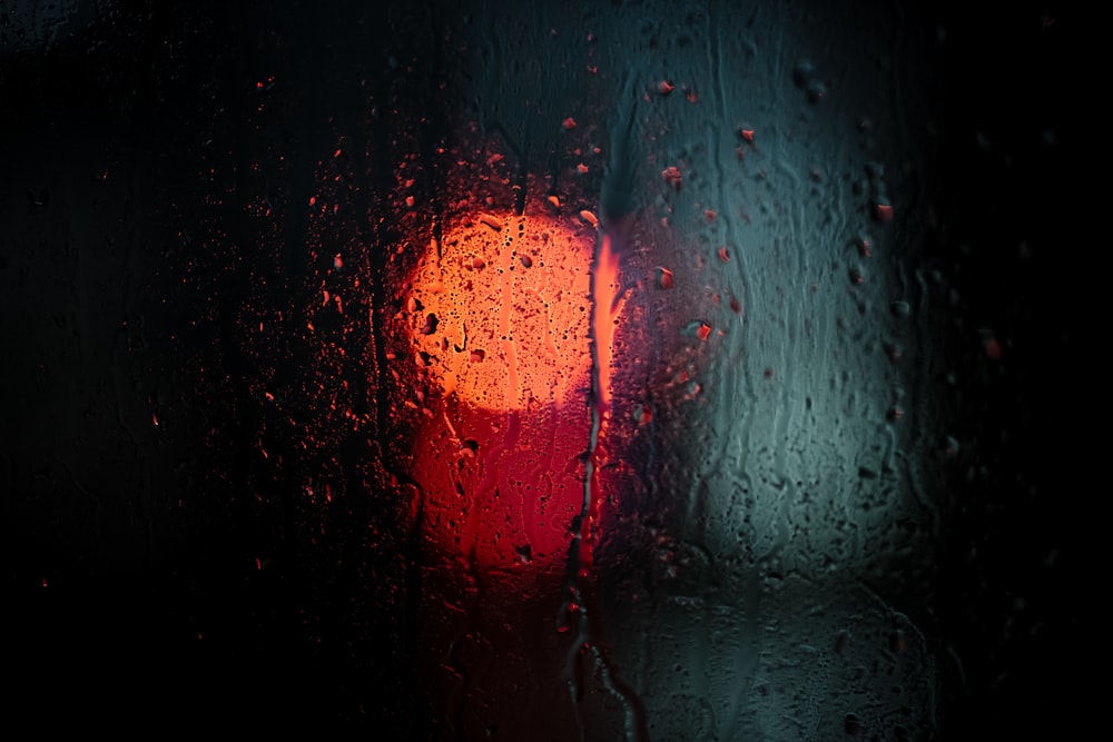 비로 덮인 창문 옆에 앉아 있는 빨간 신호등