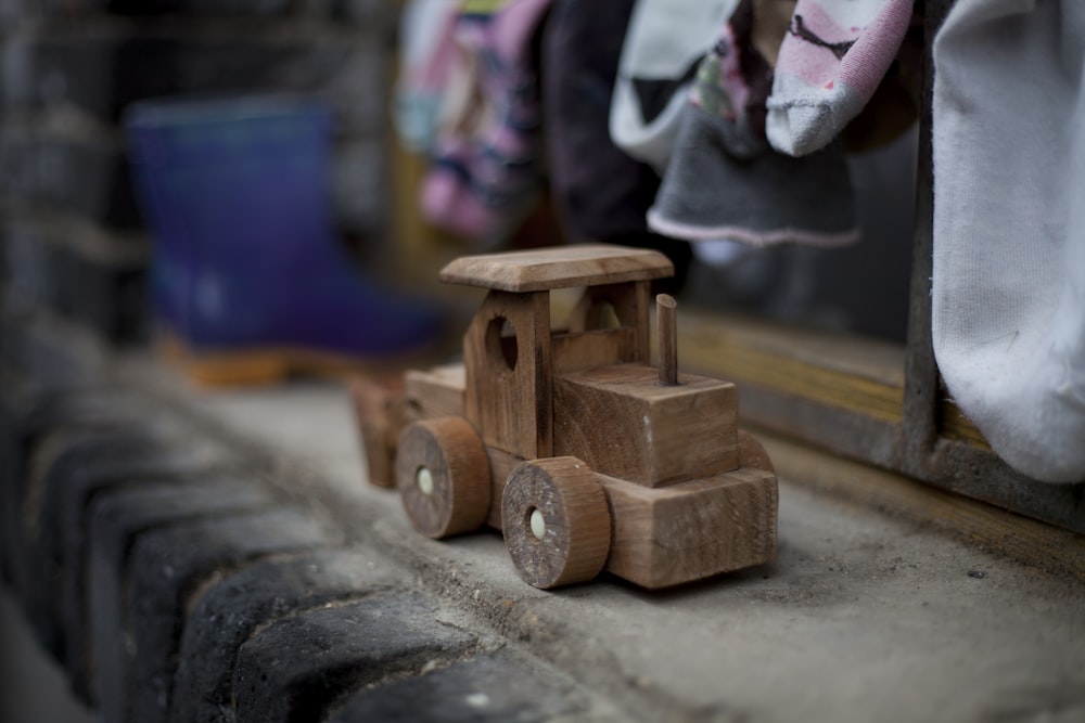 Juguete de vehículo de madera marrón sobre superficie de hormigón gris