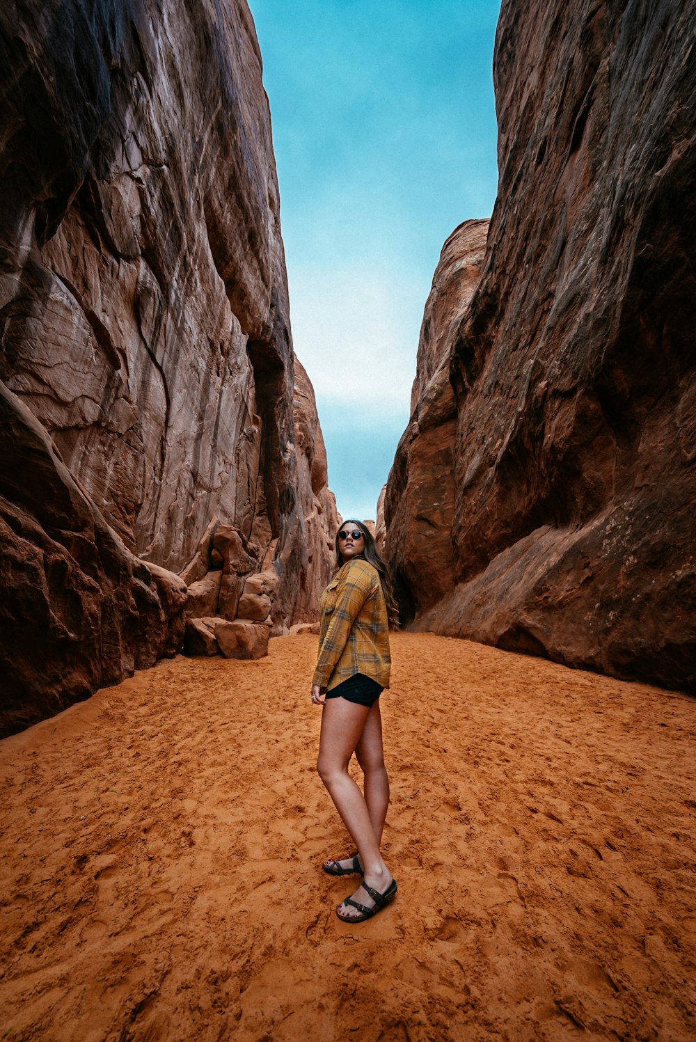 woman standing in between rock formation during daytime