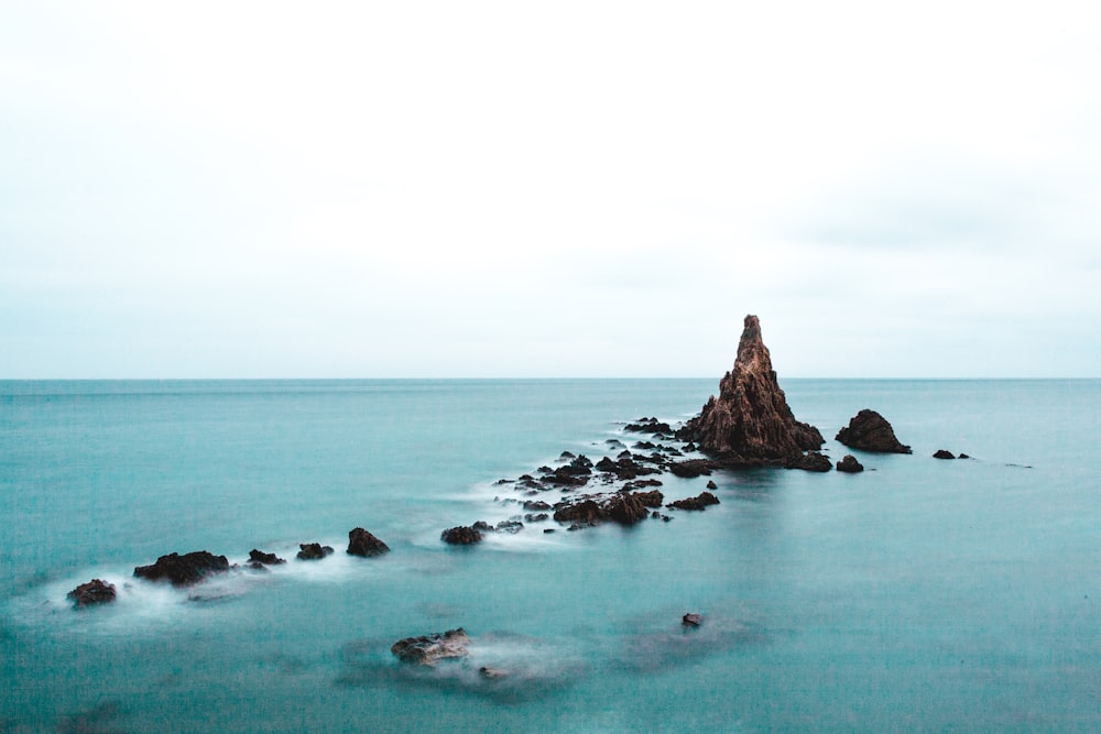 rock formation in body of water during daytime