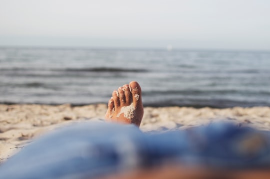 person lying on sand beside seA in Warnemünde Germany