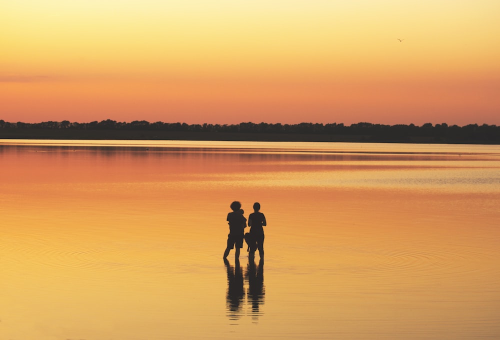two people standing on body of water during daytime